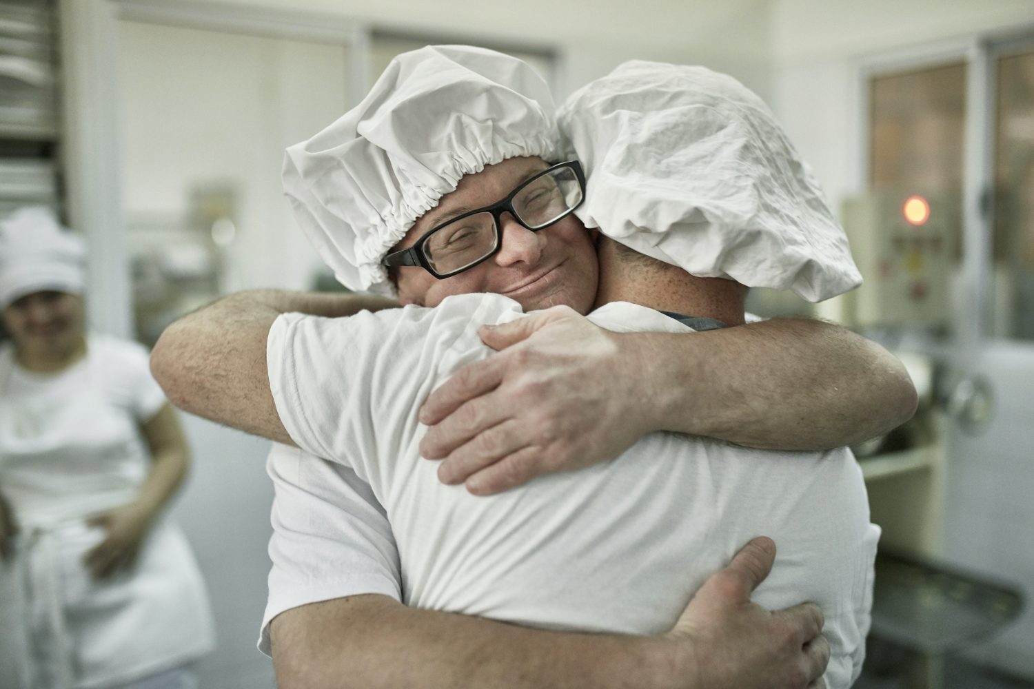 Affectionate Male Pasta Makers Embracing in Factory